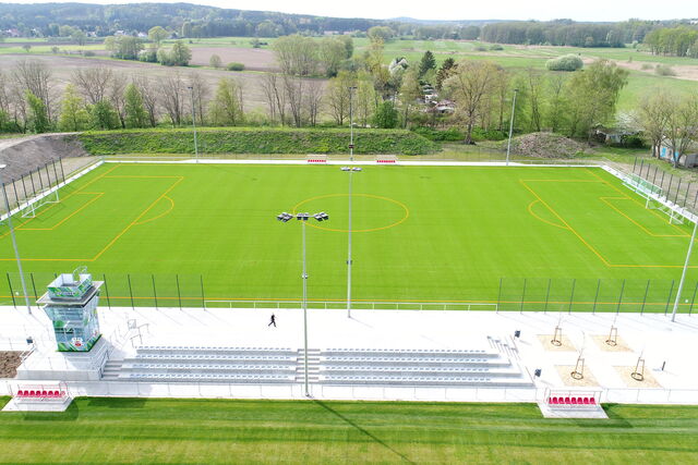 Moderne FSportanlage Kaltenborner Straße Guben mit einem neuen Kunstrasen und Tribünen, umgeben von einer malerischen Landschaft.