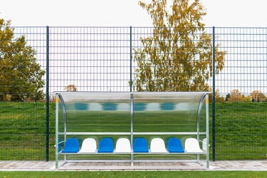 Überdachte Spielerbank mit blauen und weißen Sitzen