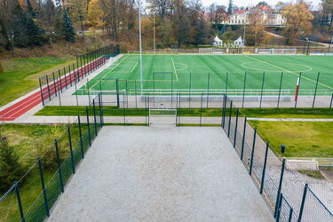 Blick auf umzäunten Zuweg zum Kunststoffrasenspielfeld