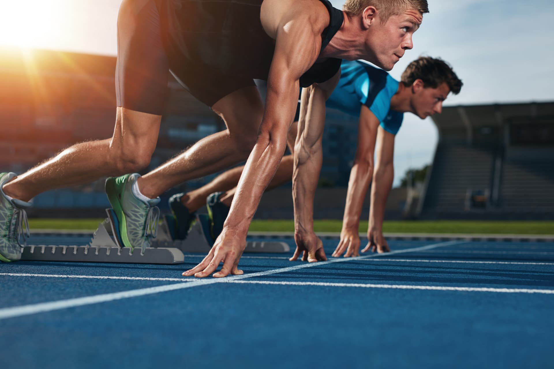 Symbolfoto Sportplatzbau: Leichtathleten auf Tartanbahn konzentrieren sich auf Tiefstart